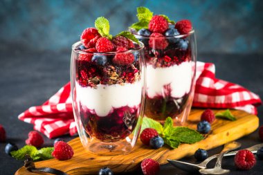 Parfait with granola, jam and fresh berries in the glass jar.