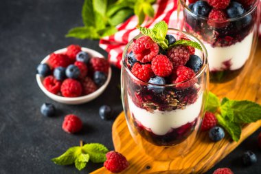 Parfait with granola, jam and fresh berries in the glass jar.