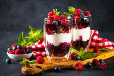 Parfait with granola, jam and fresh berries in the glass jar.