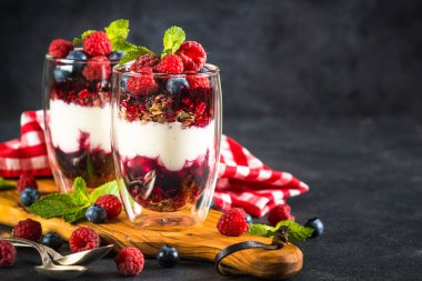 Parfait with granola, jam and fresh berries in the glass jar.