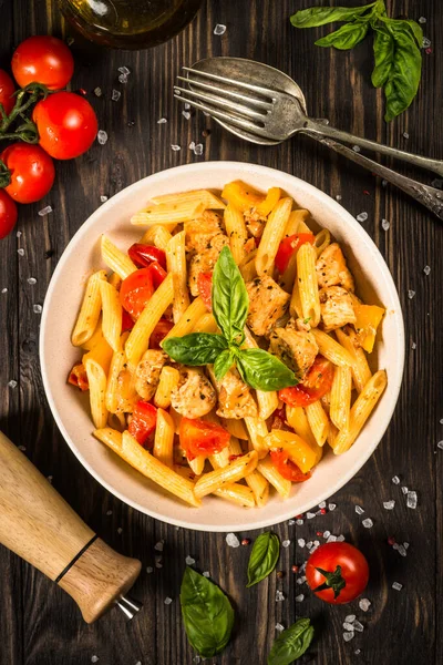 Pasta with chicken and vegetables at wooden table. — Stock Photo, Image