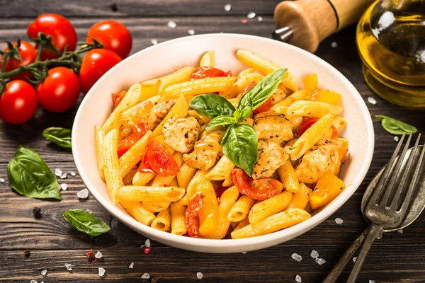 Pasta con pollo y verduras a la mesa de madera. — Foto de Stock