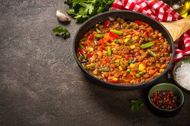 Koyu taş masada tavada Chili con carne.