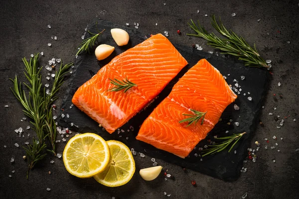 Ikan salmon dengan bahan-bahan di meja hitam. — Stok Foto