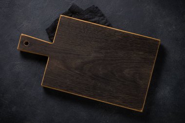 Siyah masanın üzerindeki siyah tahta kesme tahtası..