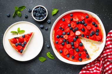 Çilekli ve yabanmersinli tart. Siyah arkaplanda üst görünüm.