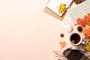 Sonbahar çalışma alanı düz arka planda yatıyordu. Laptop, defter, bir kupa baharatlı çay ve sarı yapraklı eşarp..