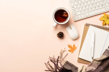 Sonbahar çalışma alanı düz arka planda yatıyordu. Laptop, defter, bir kupa baharatlı çay ve sarı yapraklı eşarp..