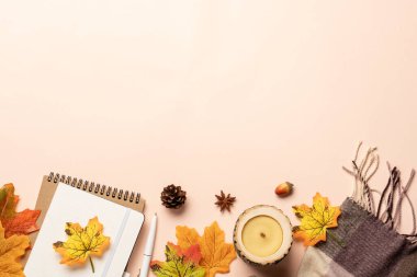 Sonbahar düz arka plan yatıyordu. Sarı arka planda sonbahar yaprakları, eşarp, mum ve baharatlar.