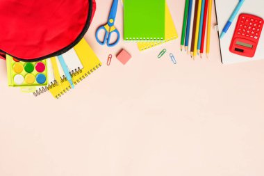 Okula dönelim. Renkli arka planda kırtasiye malzemesi olan okul çantası. Dizayn için alanı olan düz uzandı.