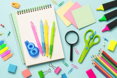 Ofis kağıtları mavi arka planda. Not defteri, kalemler, kalemler, hesap makinesi ve diğerleri. Düz görünüm.