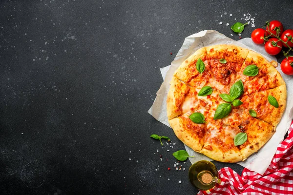 Siyah arka planda pizza margaritası ve yemek malzemeleri. Üst görünüm.