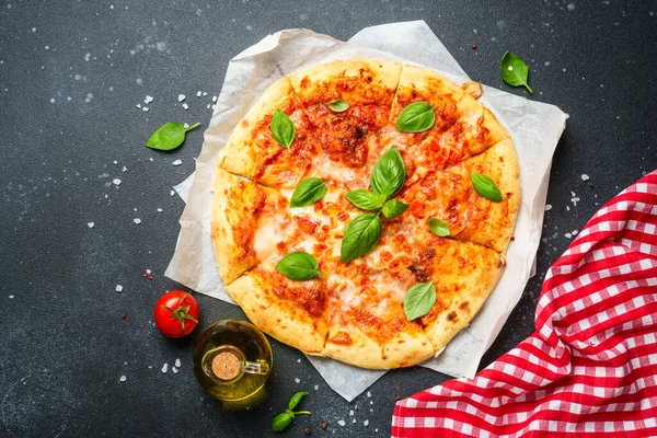 Siyah arka planda pizza margaritası ve yemek malzemeleri. Üst görünüm.