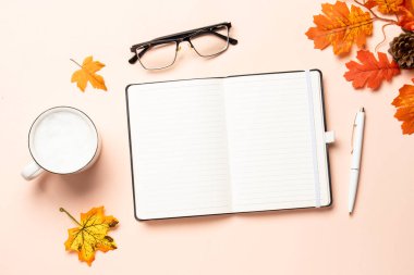 Sonbahar çalışma alanı. Not defteri, bir fincan kahve ve sarı yapraklar. Metin için boşluk ile düz uzandı.