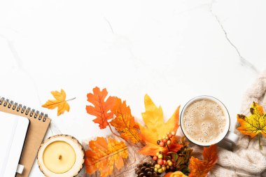 Beyaz arka planda sonbahar çalışma alanı. Not defteri, kahve kupası, rahat süveter ve sarı yapraklar. Metin için boşluk ile düz uzandı.