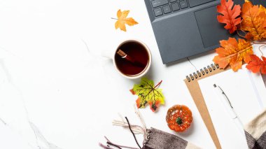 Sonbahar çalışma alanı. Laptop, defter, bir fincan çay ve dökülen yapraklar. Metin için alanı olan düz resim.