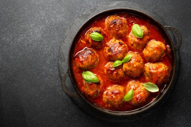 Domates soslu köfteler, siyah arka planda demir tabakta. Üst görünüm.