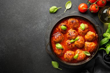 Domates soslu köfteler, siyah arka planda demir tabakta. Üst görünüm.