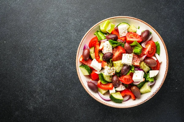 Yunan salatası siyah mutfak masasında. Kopyalama alanı olan üst görünüm. Vejetaryen yemeği.
