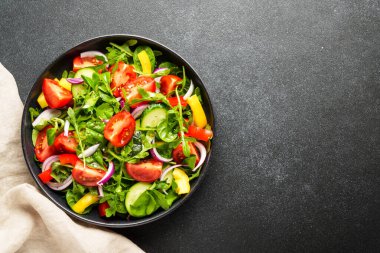 Yapraklı ve sebzeli taze salata. Siyah arkaplanda tasarım için alanı olan üst görünüm.