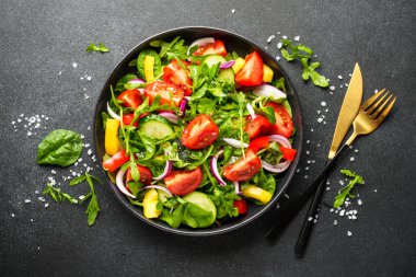 Siyah arka planda taze salata. Yapraklı salata, domates, biber ve zeytinyağı. Diyet yemek..