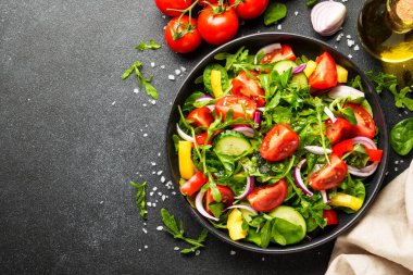 Yapraklı ve sebzeli taze salata. Siyah arkaplanda tasarım için alanı olan üst görünüm.