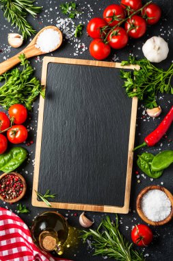 Siyahın sağlıklı yemek geçmişi. Taze sebzeler, bitkiler, baharatlar ve zeytinyağı. Kopyalama alanı olan üst görünüm, dikey.