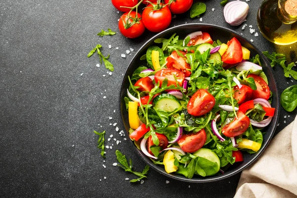 Yapraklı ve sebzeli taze salata. Siyah arkaplanda tasarım için alanı olan üst görünüm.