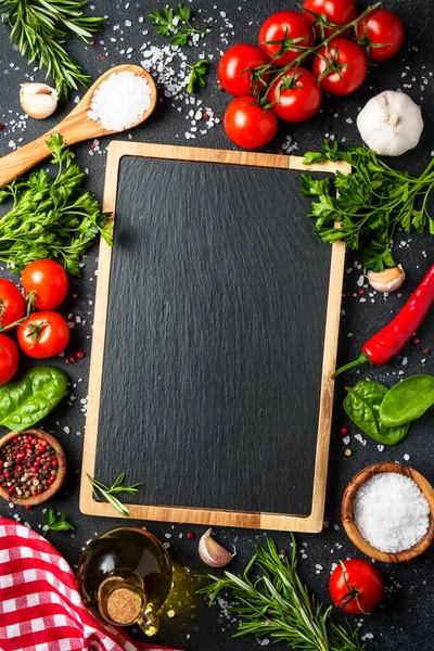 Siyahın sağlıklı yemek geçmişi. Taze sebzeler, bitkiler, baharatlar ve zeytinyağı. Kopyalama alanı olan üst görünüm, dikey.