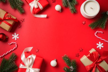 Kırmızı arka planda Noel hediyeleri. Hediye kutuları, köknar ağacı ve süslemeler..