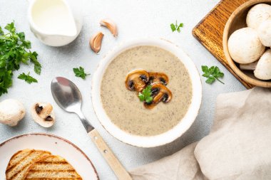 Beyaz mutfak masasında mantar çorbası püresi. Sağlıklı vejetaryen yemeği. Üst görünüm.