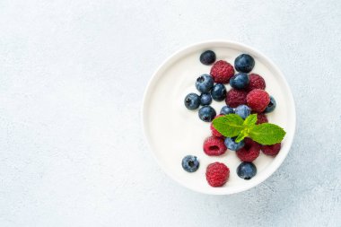 Beyaz arka planda taze böğürtlenli yoğurt. Sağlıklı atıştırmalıklar ya da kahvaltı. Tasarım için alanı olan üst görünüm.
