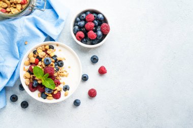Beyaz masada taze böğürtlenli yoğurt ve tahıl gevreği. Sağlıklı atıştırmalıklar ya da kahvaltı. Beyaz arkaplanda kopyalama alanı olan üst görünüm.