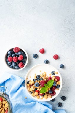 Beyaz masada taze böğürtlenli yoğurt ve tahıl gevreği. Sağlıklı atıştırmalıklar ya da kahvaltı. Beyaz arkaplanda kopyalama alanı olan üst görünüm.