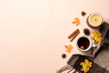 Bir kupa sıcak çay, örgü eşarp ve arka planda düşmüş yapraklar. Kopyalama alanı olan üst görünüm.