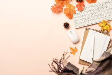 Sonbahar ofis masası. Dizüstü bilgisayar, defter, sıcak çay ve dökülen yapraklı eşarp. Metin için boşluk ile düz uzandı.