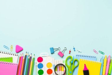 Mavi arka planda okul malzemeleri. Not defterleri, kalemler, kalemler, klipler ve diğerleri. Kopyalama alanı olan düz.