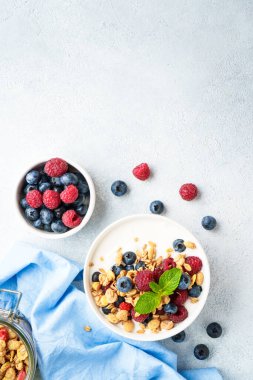 Beyaz masada taze böğürtlenli yoğurt ve tahıl gevreği. Sağlıklı atıştırmalıklar ya da kahvaltı. Beyaz arkaplanda kopyalama alanı olan üst görünüm.