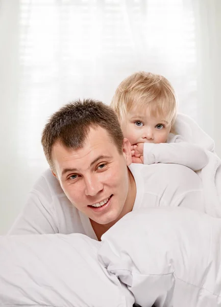 Père et enfant souriants au lit — Photo