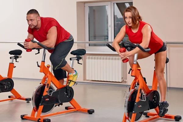 Attractive couple bycicle cycling in gym — Stock Photo, Image
