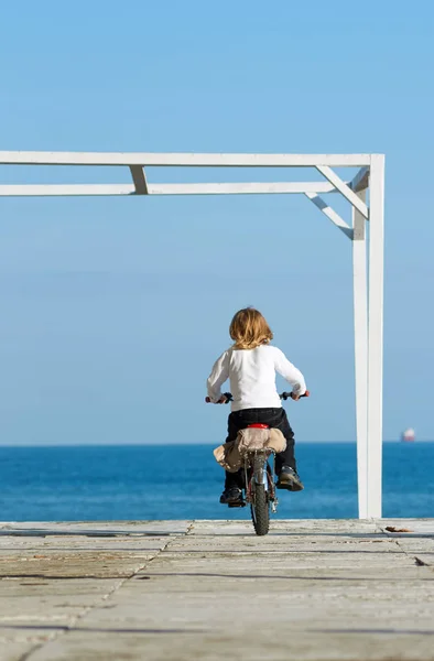 Menino andando de bicicleta sobre o mar — Fotografia de Stock