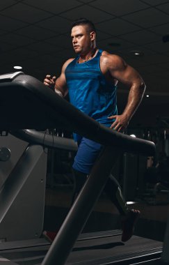 Genç atletik yakışıklı spor salonunda koşu bandı üzerinde çalışan