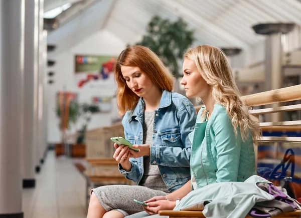 Duas mulheres com smartphone e sacos de compras — Fotografia de Stock