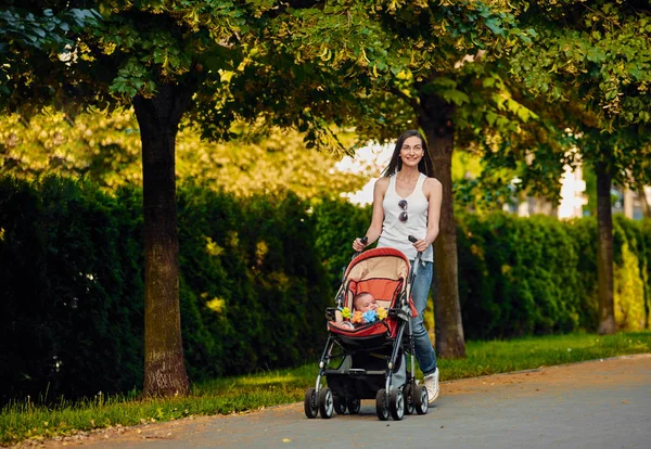 Madre con carro de bebé en el parque — Foto de Stock