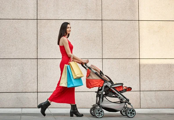 Woman walking with carriage about wall — Stock Photo, Image