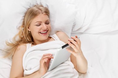 Sarışın yatakta tablet ile