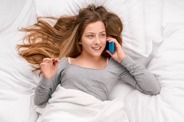 Chica con teléfono en la cama — Foto de Stock