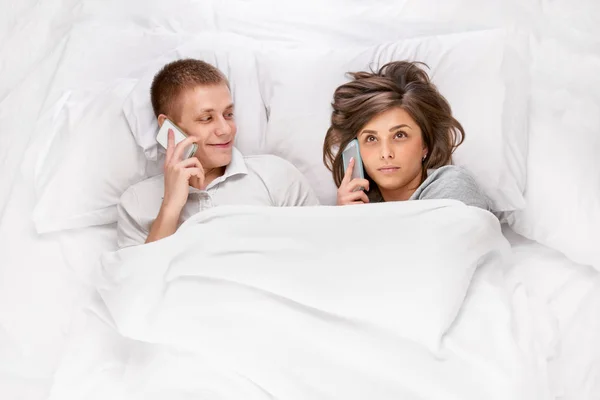Personer med smartphones i sängen — Stockfoto