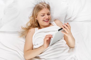 tablet ile yatakta genç sarışın