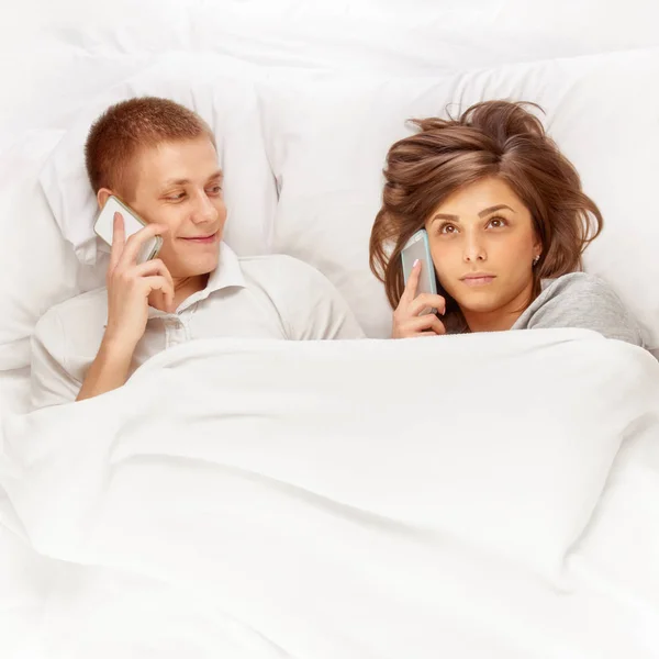 Par med smartphones i sängen — Stockfoto